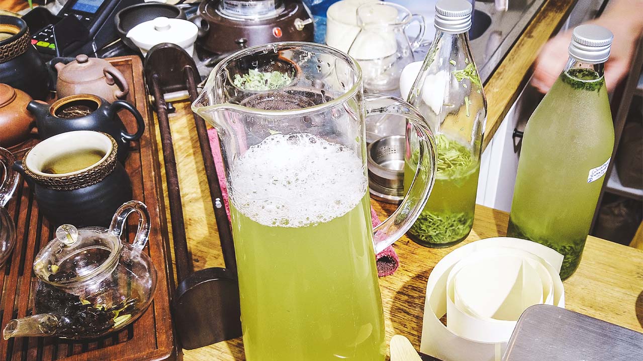 Cold brew grüntee in einer Glaskanne auf einem Tisch voll mit Teegeschir und anderen Grüntee Getränken