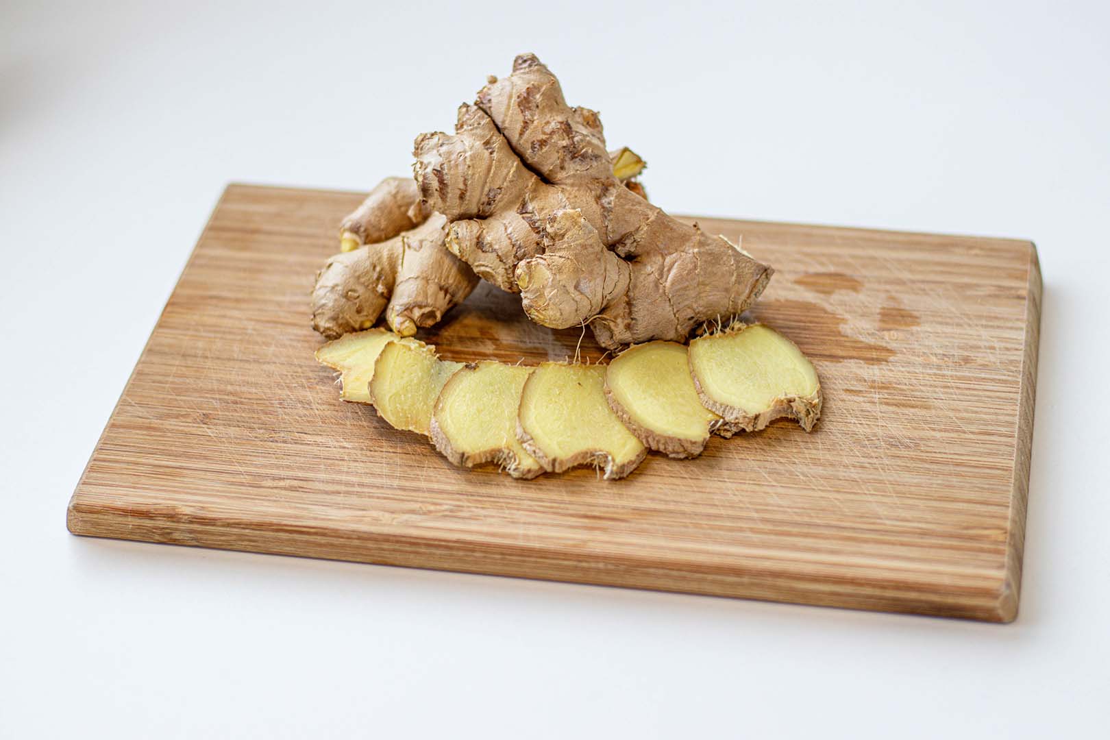 Ingwerwurzel und Ingwerscheiben auf einem Schneidebrett. Rezept für Overnight Ingwertee 