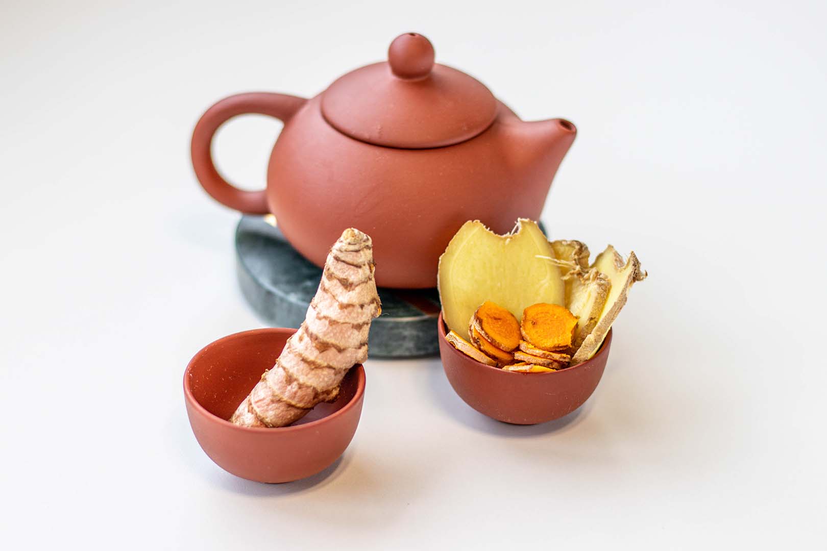 Rezeptidee für Overnight Ingwer. Asiatische Teekanne mit Kurkuma und Ingwerscheiben in Teetassen