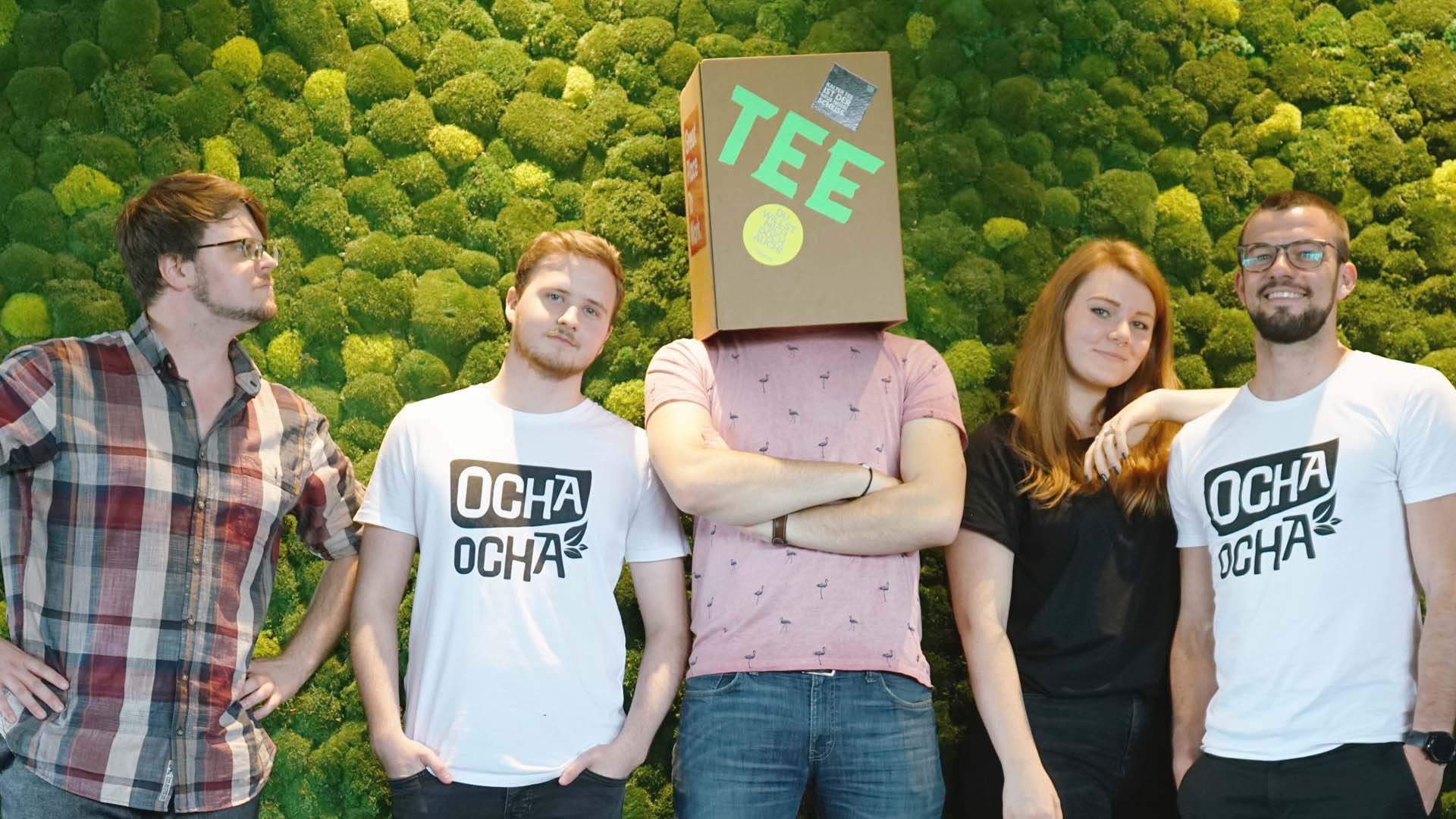 Das Ocha-Ocha® Team präsentiert sich vor einer Mooswand. Ganz links ist Chief Media Officer Denny Sachs, daneben Creative Director Fabian Kozdon und ganz rechts Gründer Christopher Gogolin.
